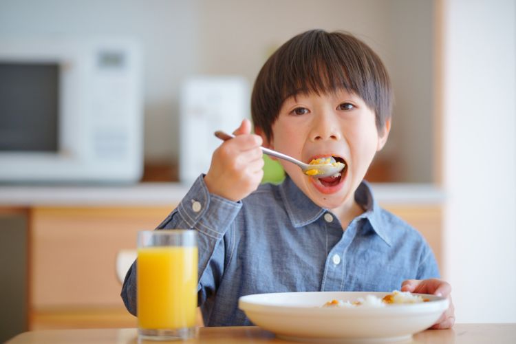 カレーをスプーンで口に運んでいる男の子